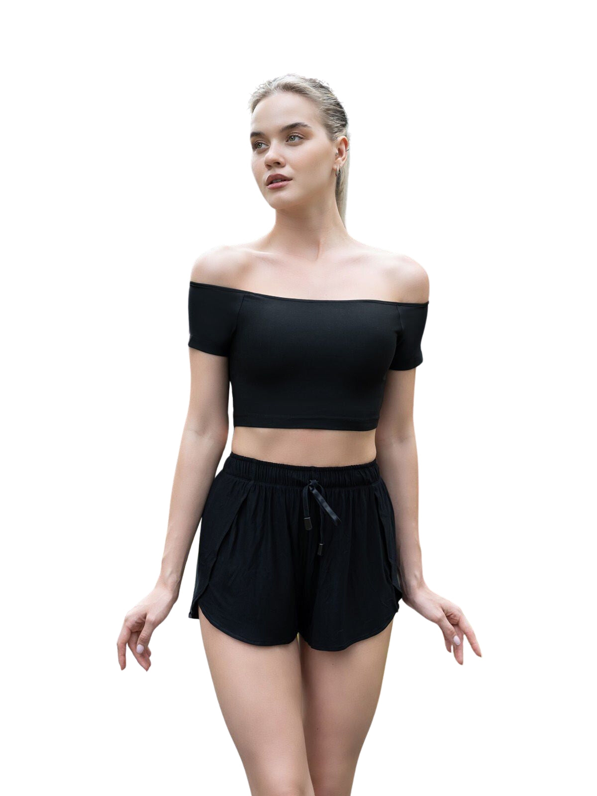 Person, die ein Lismina 084 Comfortlux Off-Shoulder-T-Shirt in Schwarz und Shorts trägt und Yoga vor einem weißen Hintergrund macht.